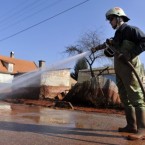A Hungarian firefighter cleans a street covered by toxic red sludge in Devecser.