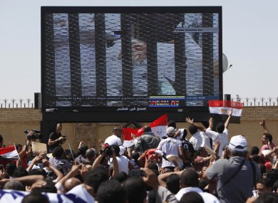 Egypt's ousted President Hosni Mubarak is seen on TV screen as he enters the courtroom on a hospital bed, outside the Police Military Academy complex in Cairo.