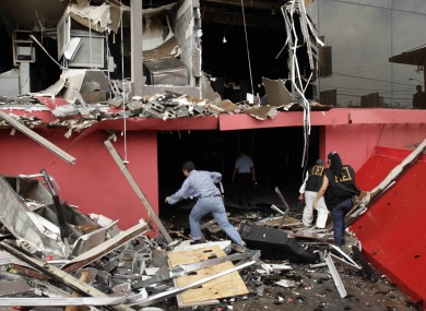 Investigators walk through debris of the charred Casino Royale after a deadly arson assault, in Monterrey, Mexico