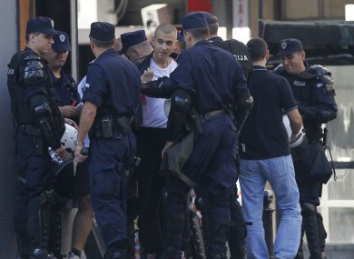 Serbian police officers detain a man, center, as a precautionary measure in downtown Belgrade today