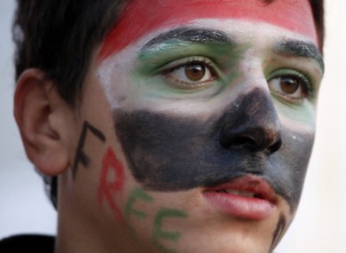 A Syrian teenager wears colors of the national flag at a protest in front of the Syrian embassy in Amman, Jordan