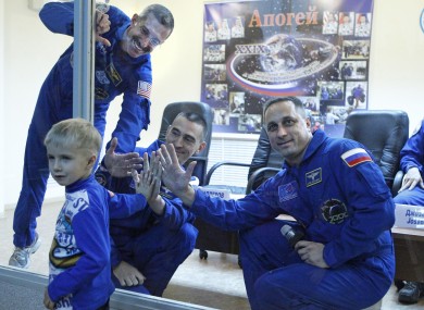 US astronaut Dan Burbank, left, Russian cosmonauts Anton Shkaplerov, right, and Anatoly Ivanishin, centre, hold their hands against safety glass with Maksim, winner of a space poster competition, at the Baikonur cosmodrome prior to the launch.