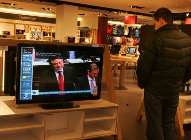 A man watches Brendan Howlin make his Budget announcement in a shop window today