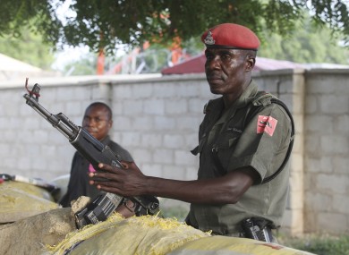 police officers armed with AK-47 rifles stand guard at sandbagged bunkers along a major road in Maiduguri, Nigeria