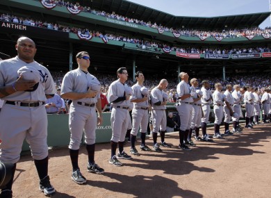 New York Yankees players stand for the national anthem in throw-back uniforms.