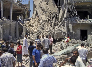 Members of the media and others examine the remains of a damaged residential building in Tripoli last June