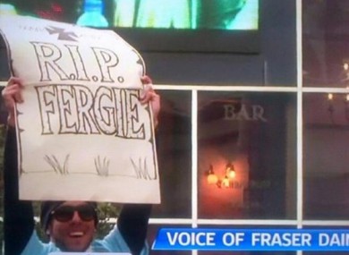 Tevez holds the sign aloft in Manchester city centre last evening.