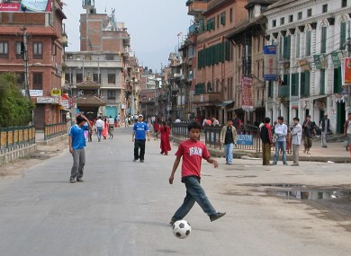 Nepalese boys play football on a traffic free street in Katmandu, Nepal