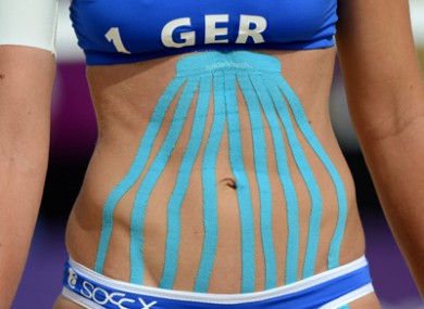 Germany’s Katrin Holtwick wears the Kinesio tape on her stomach during a beach volleyball match.