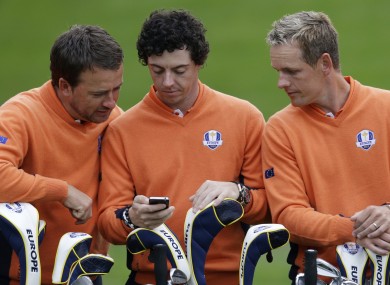 Europe's Graeme McDowell, left, and Luke Donald check TheScore app on Rory McIlroy's phone during the team photo. Probably.