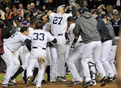 New York Yankees' Raul Ibanez (27) is mobbed by teammates at home plate after he hit the game-winning home run in the 12th inning.