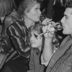 Actress Mariel Hemingway, left, sips from a glass while eyeing the crowd as actress Drew Barrymore, center, and her friend Bruce Thomas watch the fashions at Pat Kerr's show, held in New York's Hard Rock Cafe, November 1984.
(AP Photo/Ray Stubblebine)