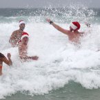 Wet and cold weather hasn't discourage British travelers, left to right, Isolde Lewis, Spencer Sullivan, Damon Hull, Lewis Conlon and Daniel Strange, as they celebrate Christmas Day at Bondi Beach in Sydney, Australia. (AP Photo/Rick Rycroft)