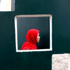 An Acehnese woman is seen through an opening on a wall as she attends a prayer commemorating the 8th anniversary of the Indian Ocean tsunami in Banda Aceh, Aceh province, Indonesia. The disaster killed more than 100,000 people in the province. (AP Photo/Heri Juanda)