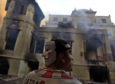 An Egyptian protester stands next to a burning school building during clashes between protesters and riot police near Tahrir Square in Cairo yesterday